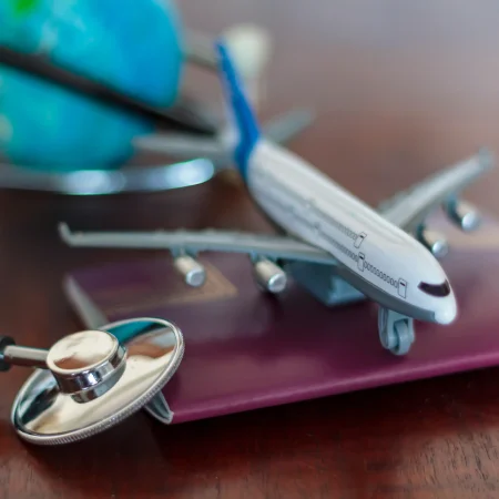 Un avion posé sur un passeport avec un stéthoscope qui soutient l'idée de souscrire une assurance voyage en cas de souci en vacances